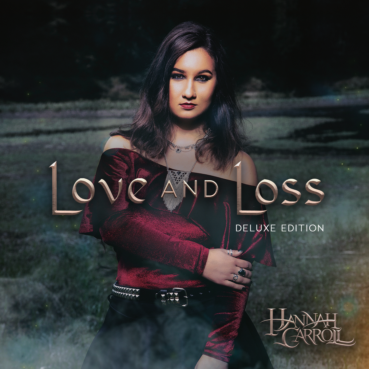 Love and Loss deluxe cover of Hannah Carroll in red blouse, black skirt, and gothic jewelry standing in green grass